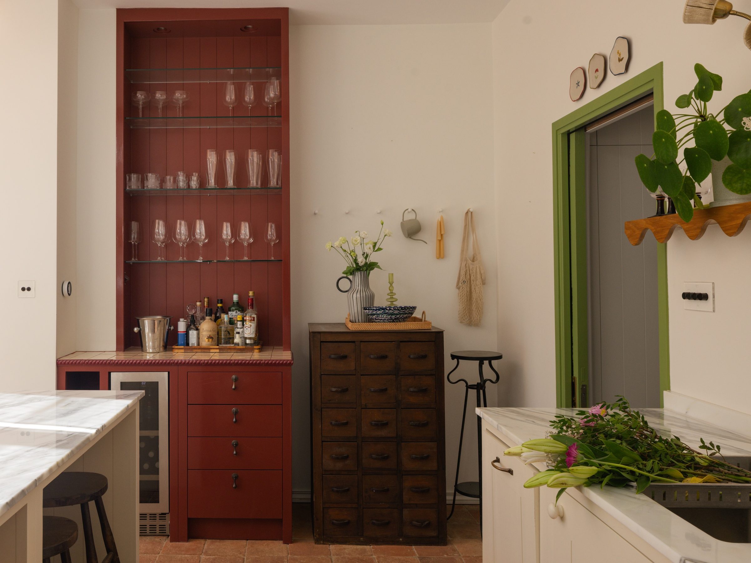 Red painted bar cabinet beside an antique chest of drawers