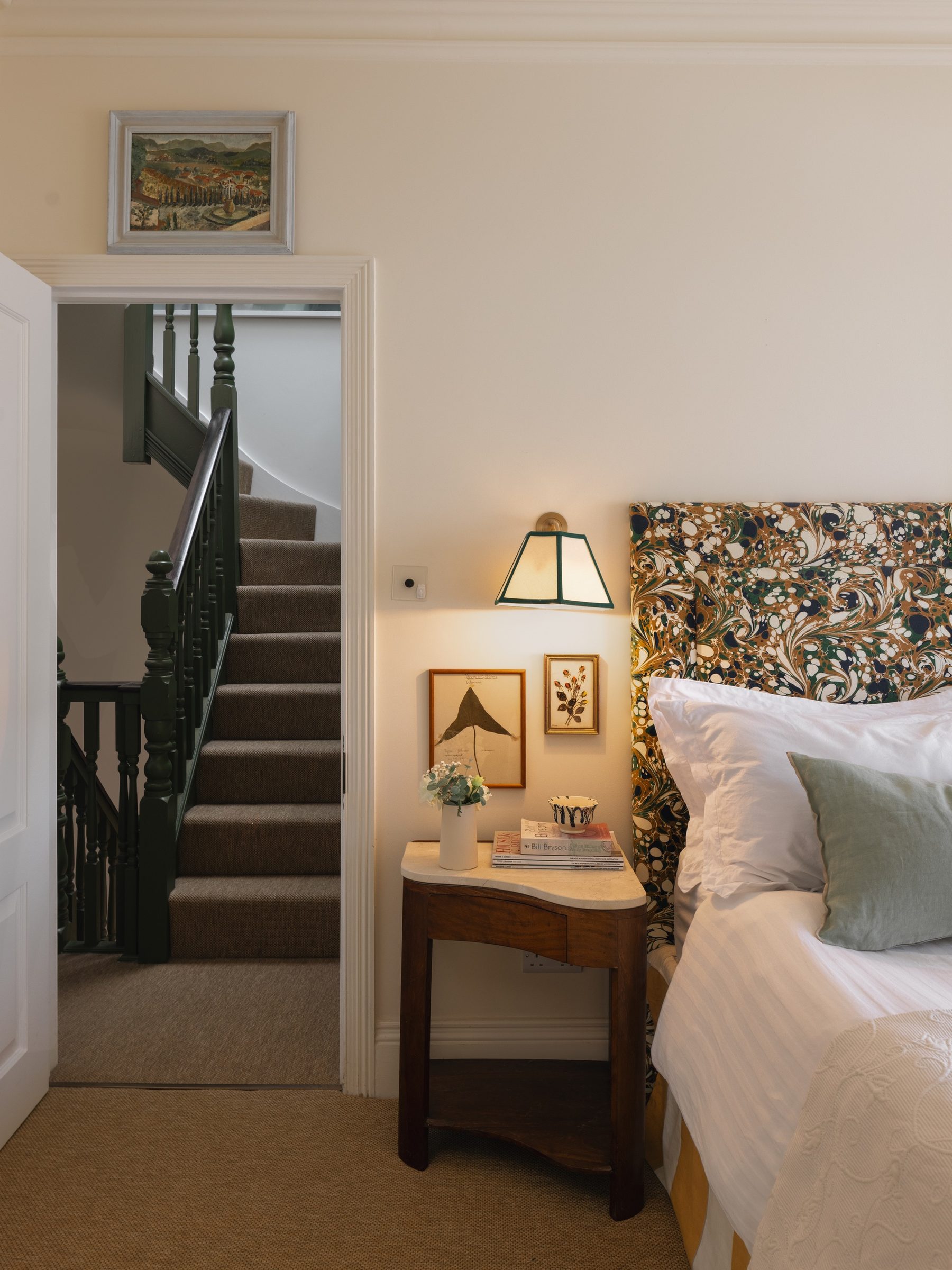 Bedside lamp and marbled headboard by the stair door