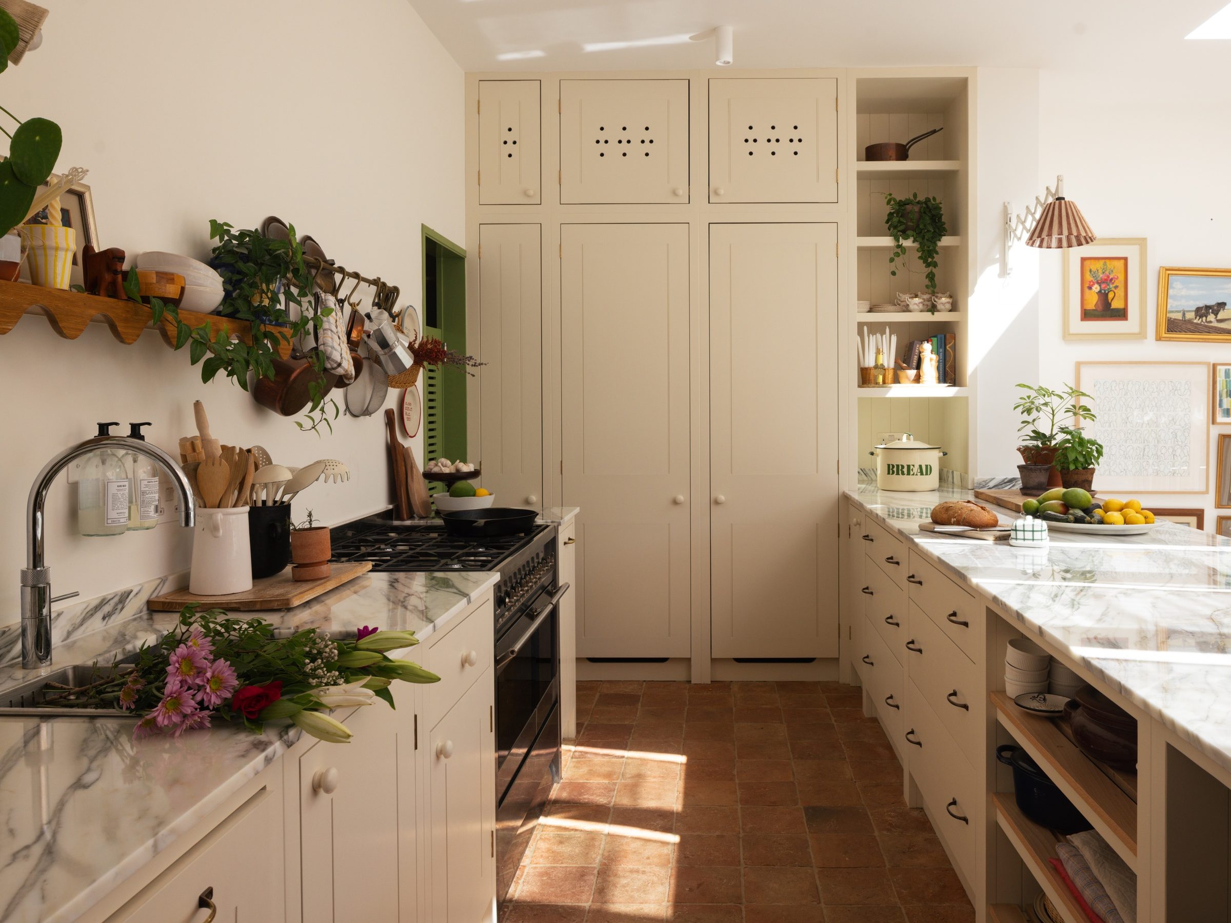 Cream kitchen with marble worktops and a terracotta tiled floor