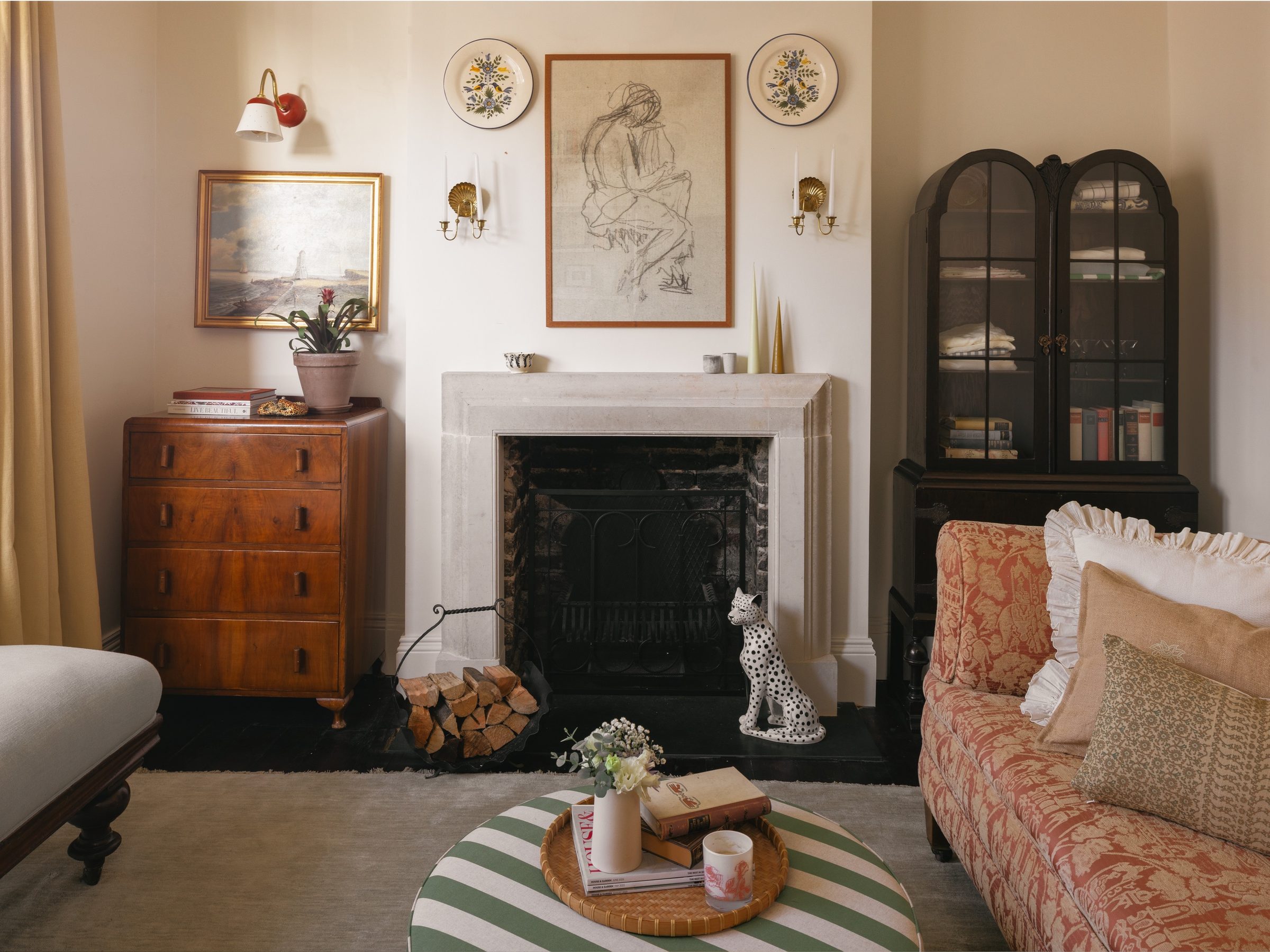 Living room with a stone fireplace, antique furniture and patterned sofa