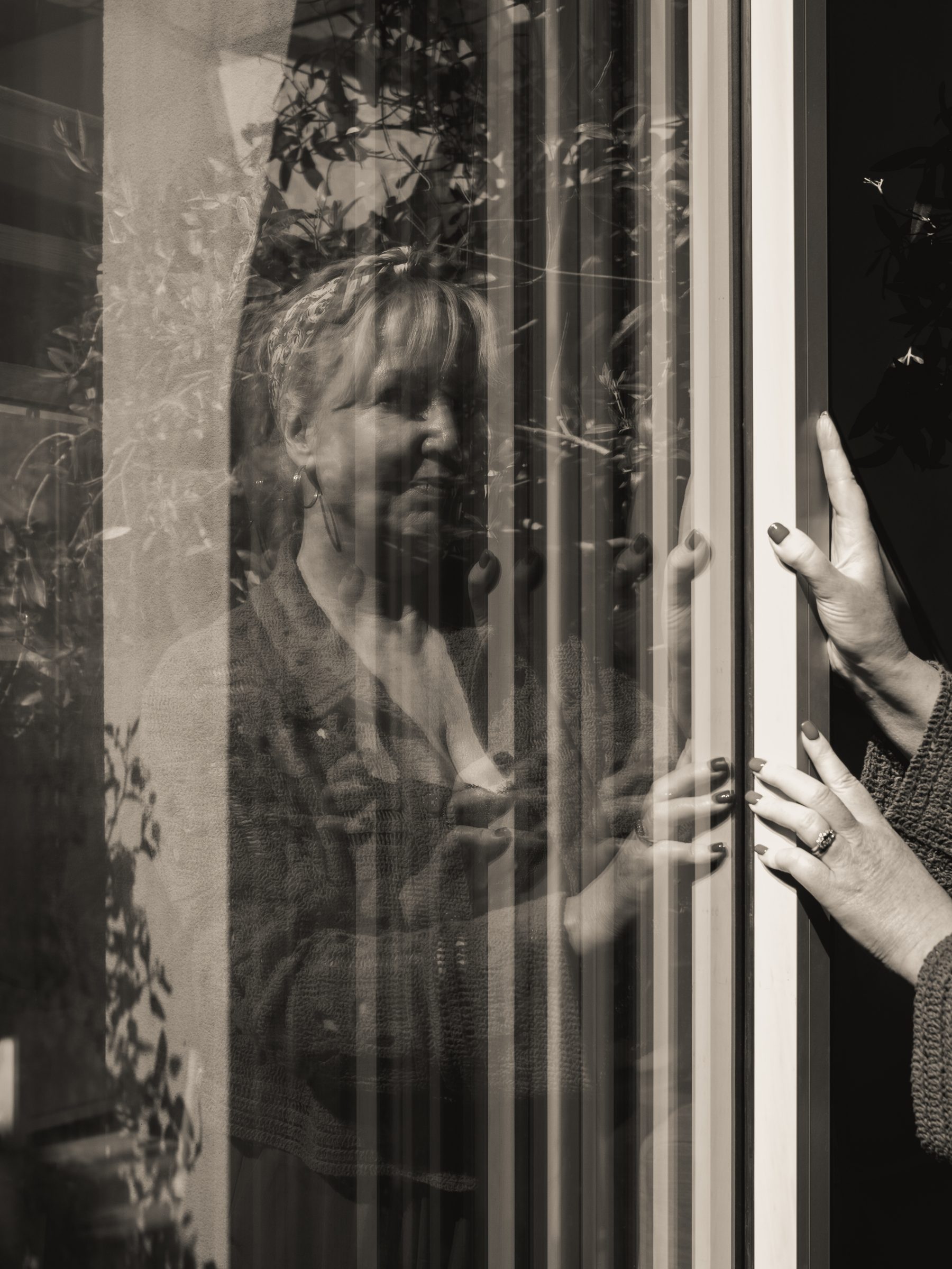 Hands on the glass doors, in black and white