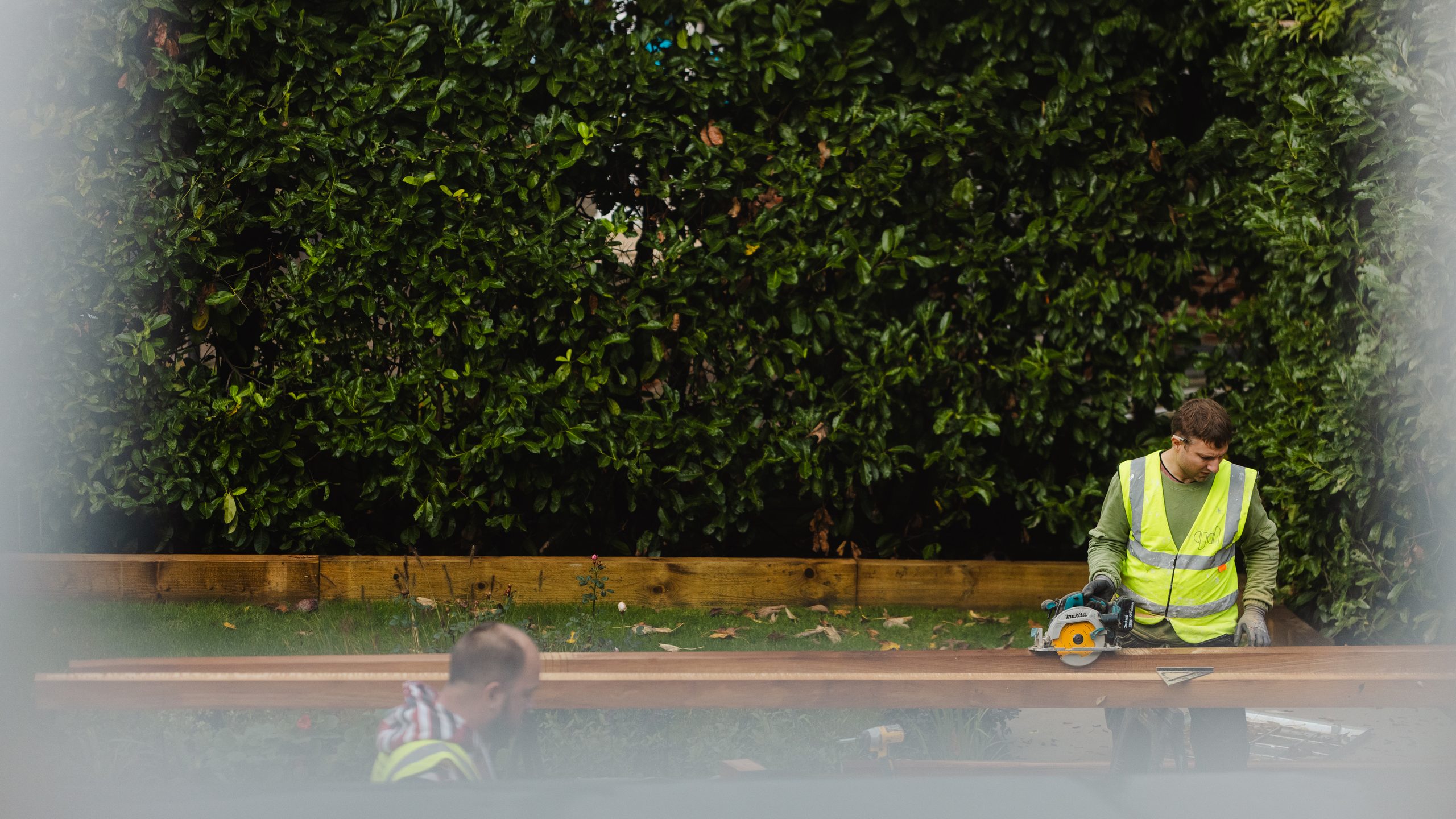 Worker cutting timber in the garden at Winnington Road
